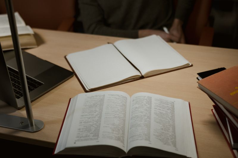 Open books and a notebook beside a laptop
